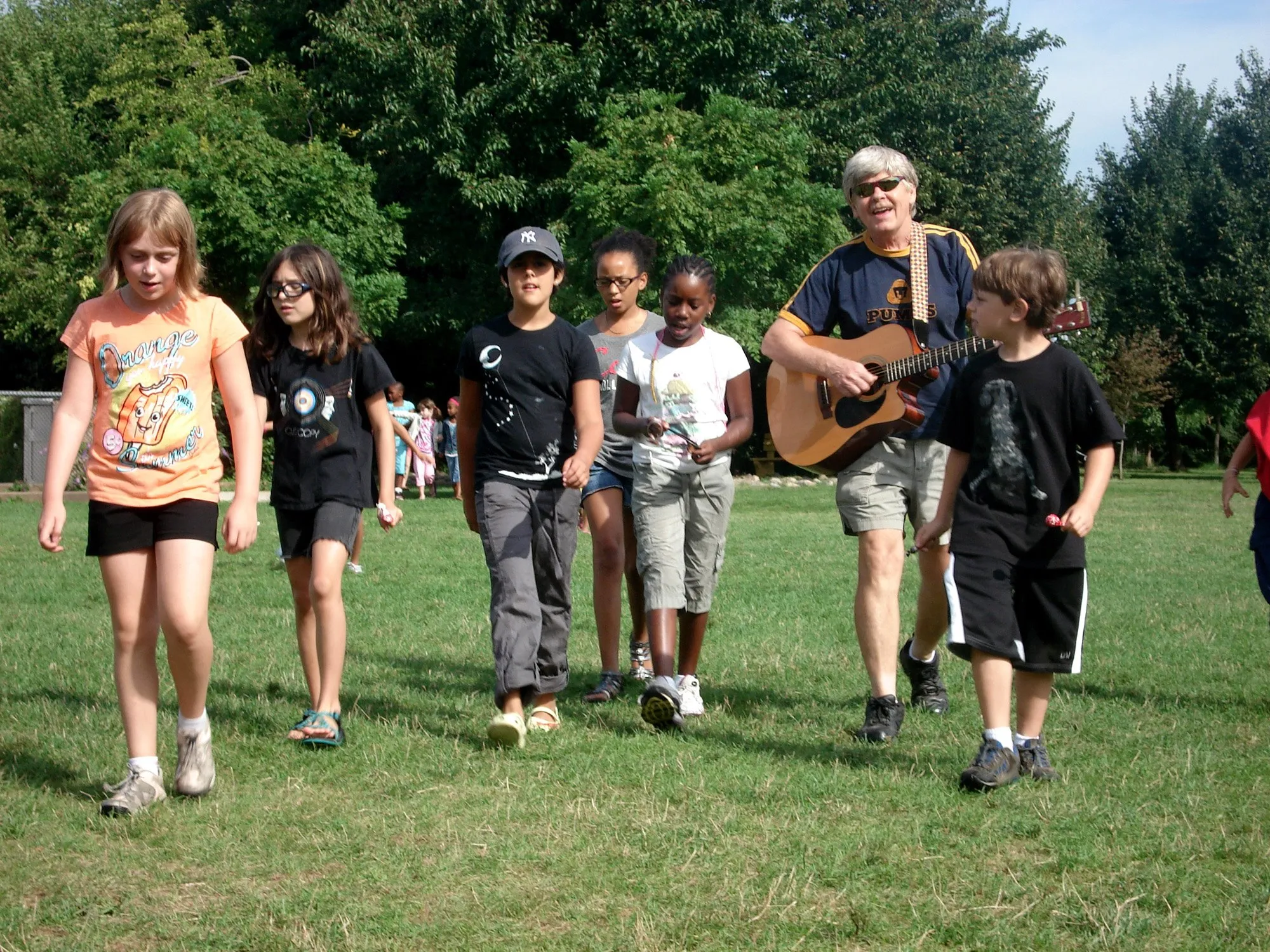 Robert walking with kids holding a guitar